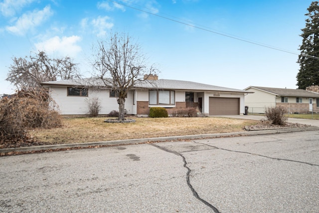 single story home featuring fence, concrete driveway, an attached garage, brick siding, and a chimney