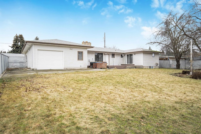 back of property with fence, a chimney, a garage, a jacuzzi, and a lawn