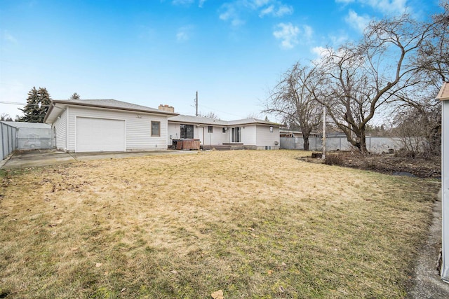 rear view of property with an attached garage, a yard, and fence