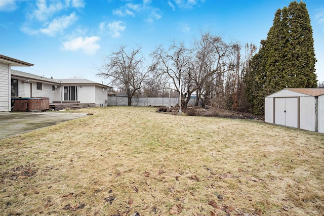 view of yard with fence, an outdoor structure, a storage shed, a jacuzzi, and a patio area