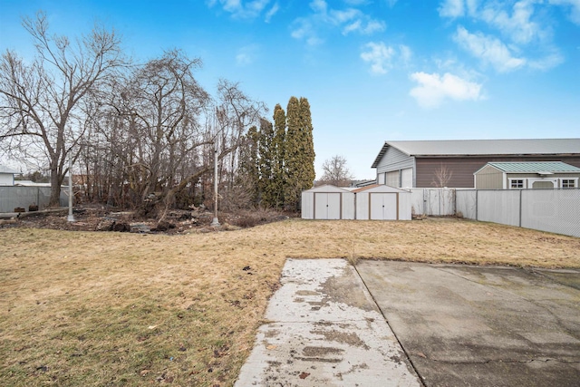 view of yard featuring a storage shed, fence, and an outbuilding