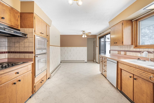 kitchen featuring a wealth of natural light, a wainscoted wall, white appliances, wallpapered walls, and light floors