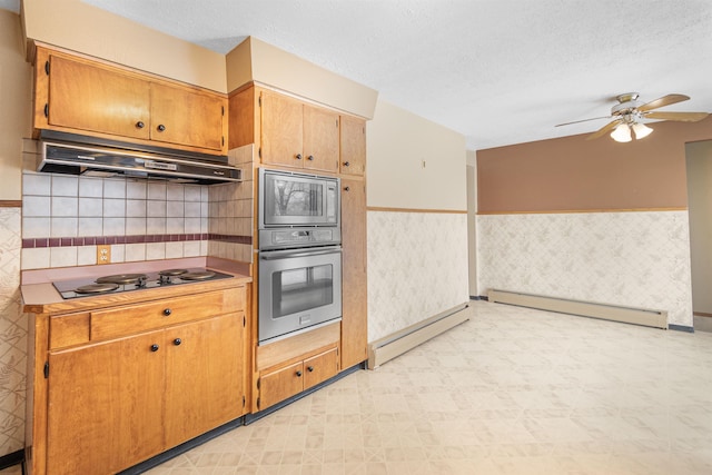 kitchen featuring under cabinet range hood, baseboard heating, light floors, and stainless steel appliances