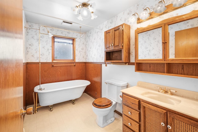 full bath with a wainscoted wall, a soaking tub, vanity, and wallpapered walls