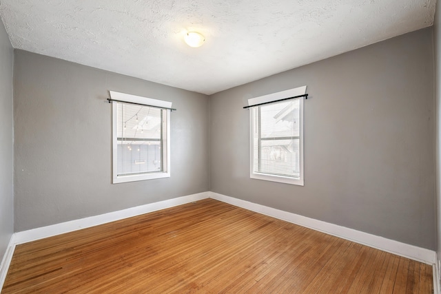 empty room with baseboards, a healthy amount of sunlight, and wood finished floors