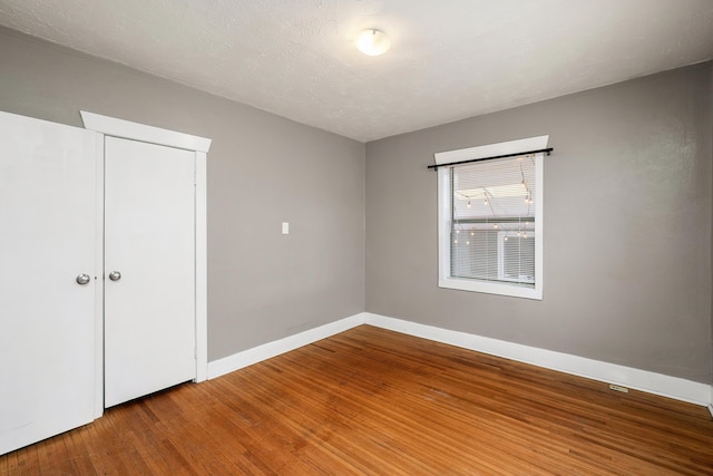 empty room featuring wood finished floors, baseboards, and a textured ceiling