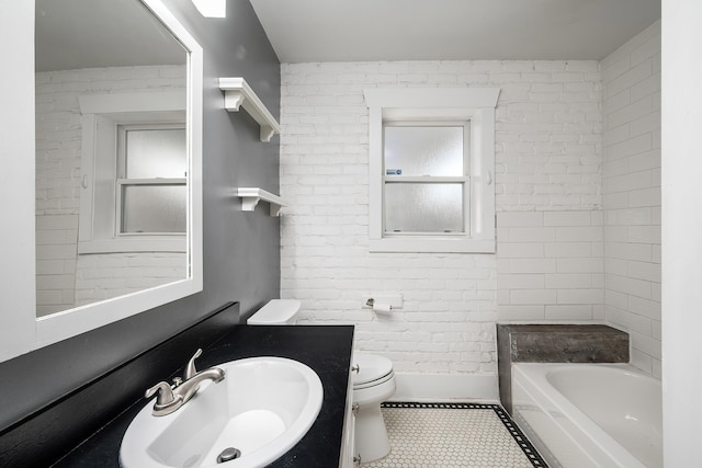 bathroom featuring vanity, tile patterned floors, toilet, and brick wall