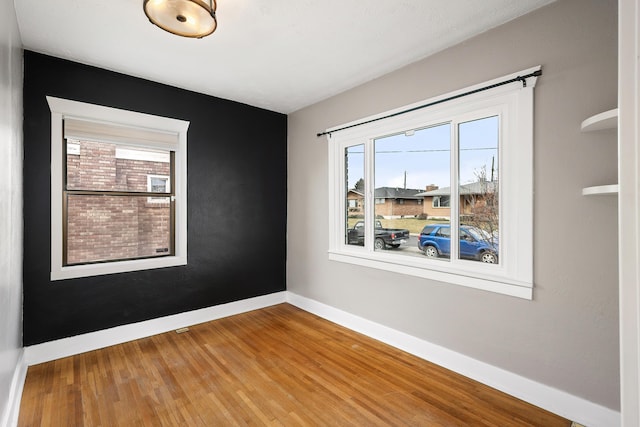 spare room with baseboards and wood finished floors