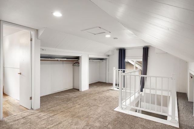 unfurnished bedroom with recessed lighting, light colored carpet, multiple closets, and vaulted ceiling