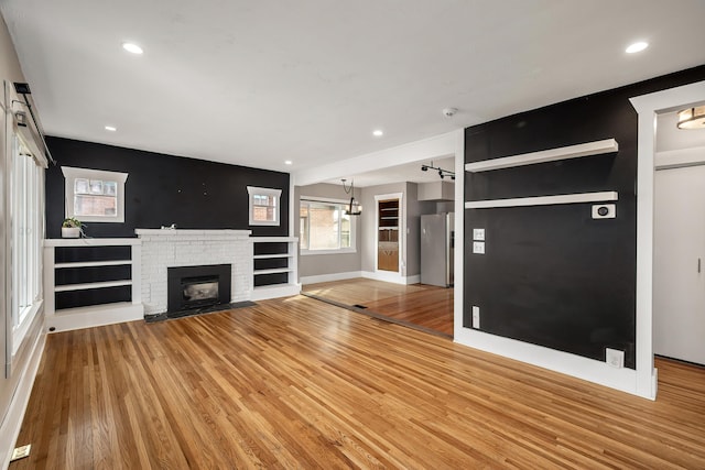 unfurnished living room featuring recessed lighting, a brick fireplace, baseboards, and light wood-style floors