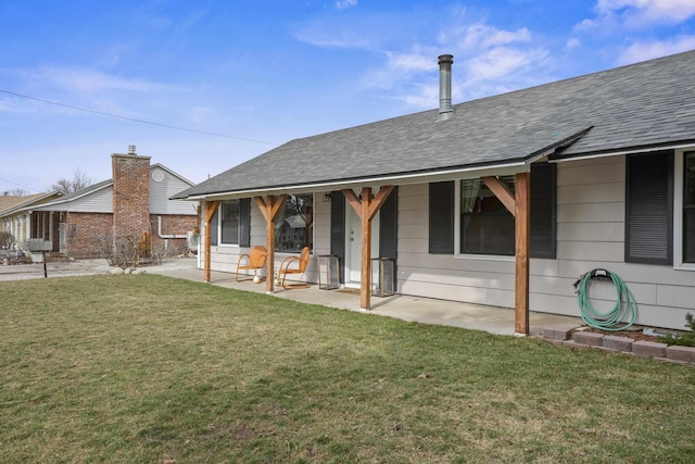 back of house featuring a yard, a patio area, and a shingled roof