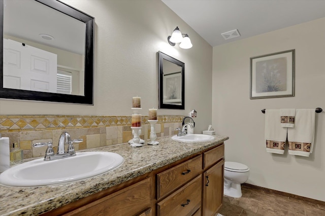 bathroom featuring double vanity, toilet, baseboards, and a sink