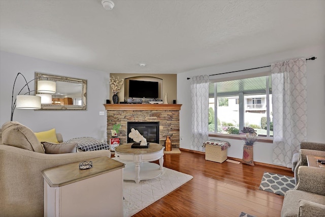 living room featuring a fireplace, baseboards, and wood finished floors