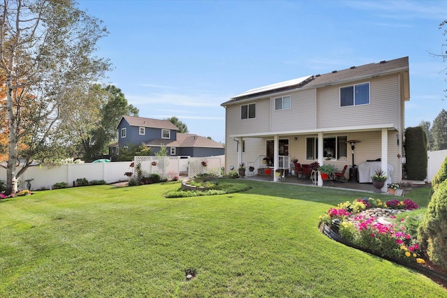 rear view of house with a patio, a lawn, and a fenced backyard