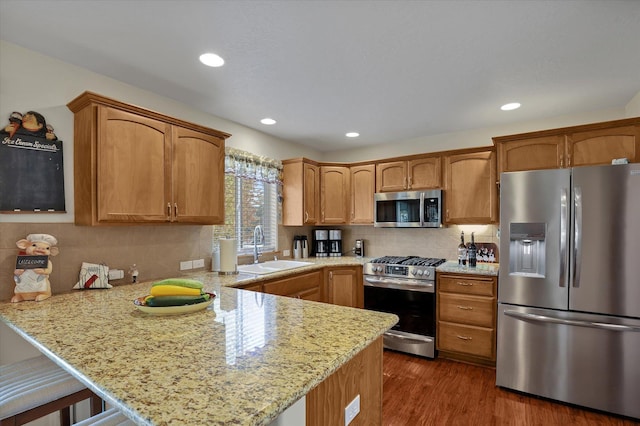 kitchen with a sink, backsplash, a peninsula, stainless steel appliances, and dark wood-style flooring