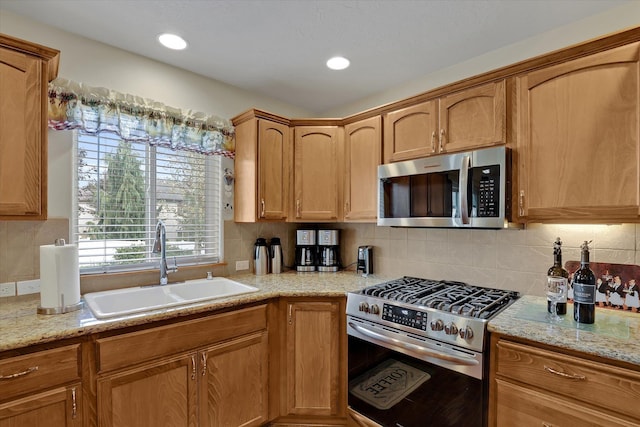 kitchen featuring light stone counters, recessed lighting, a sink, appliances with stainless steel finishes, and backsplash