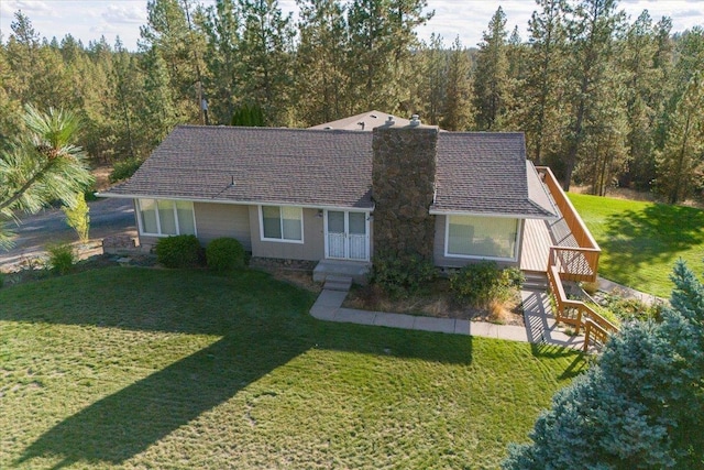 view of front of property with a chimney, a wooded view, and a front yard