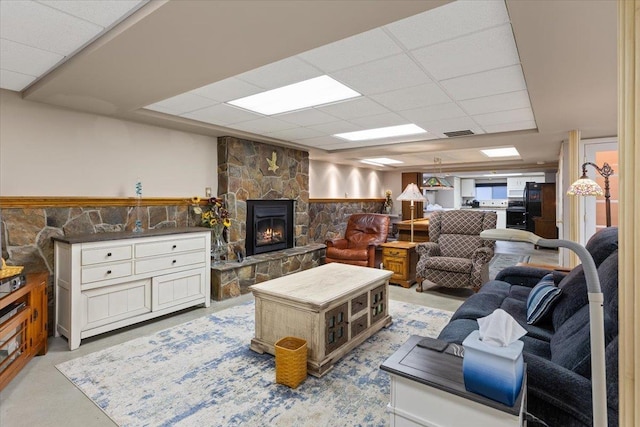 living area featuring a drop ceiling, a fireplace, visible vents, and finished concrete floors