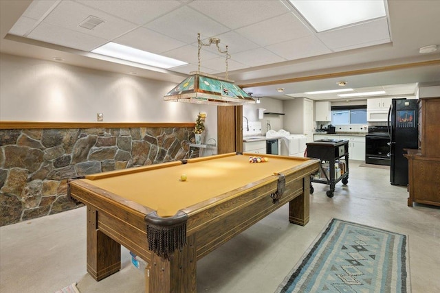 game room with a sink, a paneled ceiling, concrete flooring, and washing machine and clothes dryer