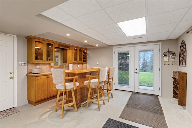 dining area with bar area, french doors, visible vents, and a paneled ceiling