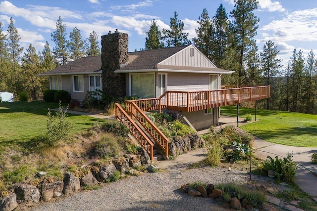 view of front of home with a front yard, a chimney, stairs, a deck, and board and batten siding