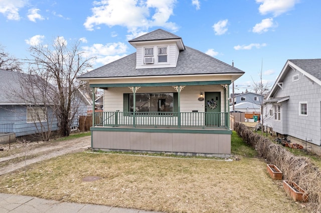 view of front of house featuring a front yard, covered porch, and roof with shingles