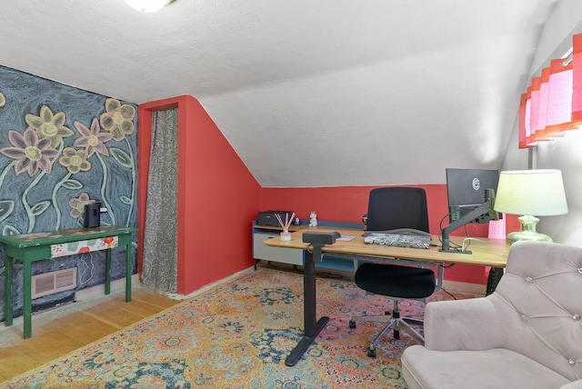 office area featuring wood finished floors, visible vents, baseboards, lofted ceiling, and a textured ceiling