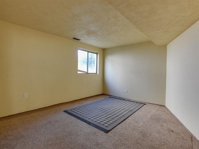 empty room featuring visible vents, carpet, and a textured ceiling