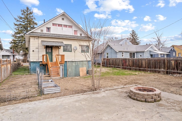 rear view of property featuring fence and an outdoor fire pit