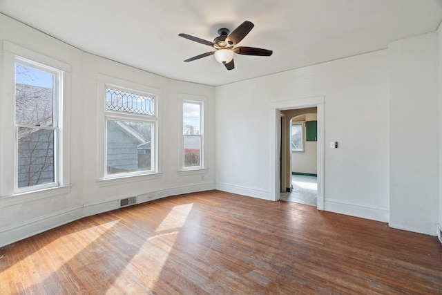 unfurnished room with a ceiling fan, wood finished floors, and baseboards