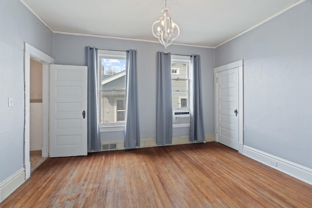 unfurnished room with visible vents, a notable chandelier, wood finished floors, and crown molding