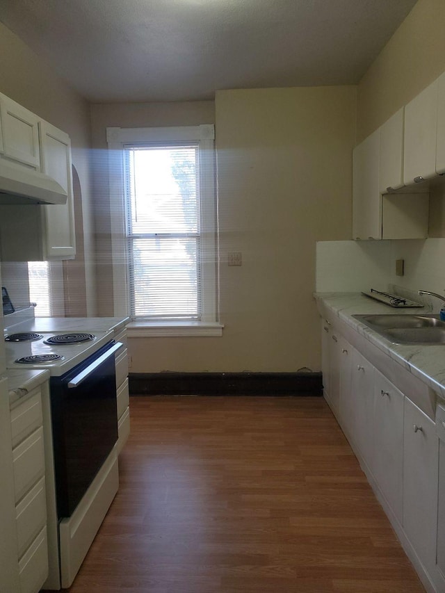 kitchen with electric range, a sink, white cabinets, under cabinet range hood, and light wood-type flooring