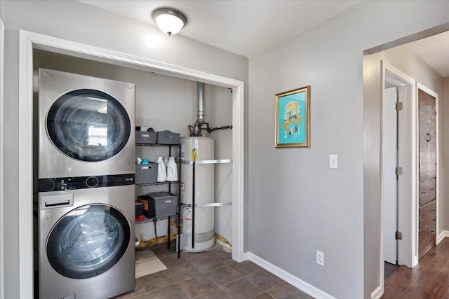 laundry room featuring laundry area, secured water heater, stacked washer and clothes dryer, and baseboards