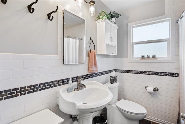 full bath with curtained shower, a wainscoted wall, toilet, tile walls, and a sink