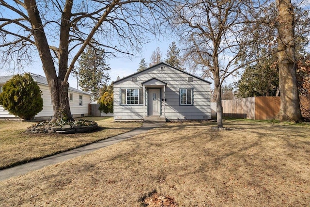 bungalow-style home featuring a front lawn and fence