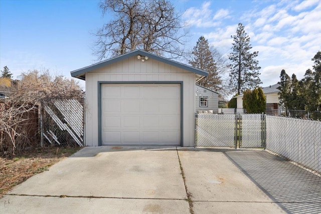 detached garage featuring a gate, driveway, and fence