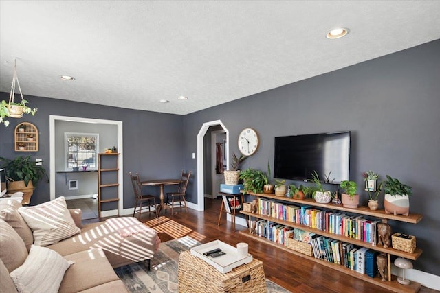 living room featuring recessed lighting, wood finished floors, arched walkways, and baseboards