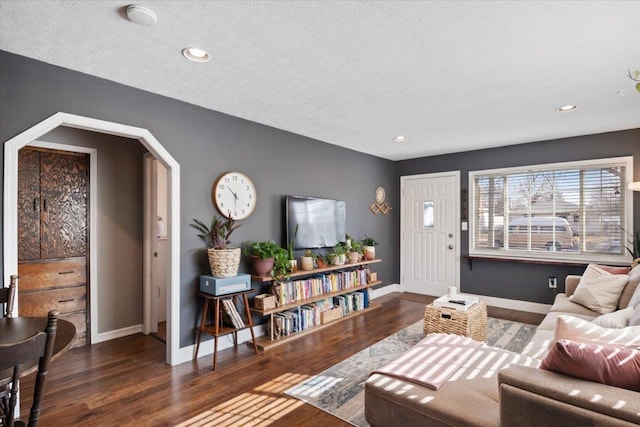 living area with arched walkways, recessed lighting, baseboards, and wood finished floors