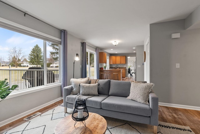 living room featuring light wood-type flooring, visible vents, baseboards, and recessed lighting