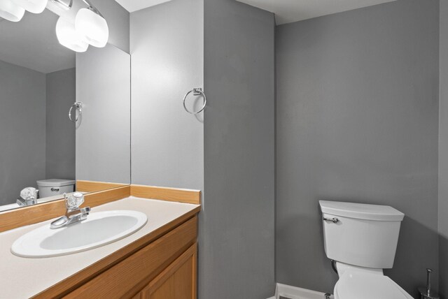 bathroom with baseboards, toilet, and vanity