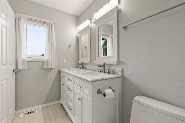 bathroom with baseboards, wood finished floors, visible vents, and a sink