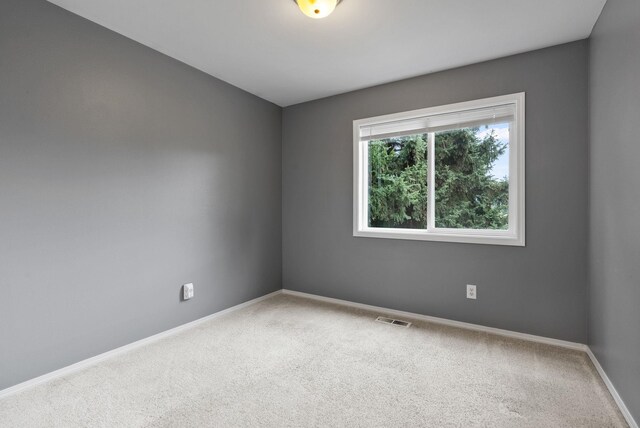 spare room featuring baseboards, visible vents, and carpet floors