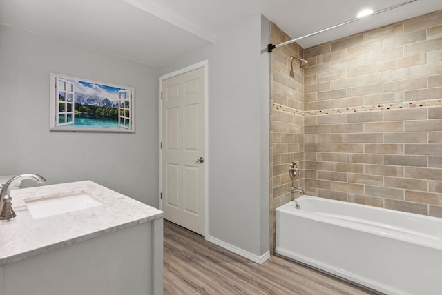 full bath featuring vanity, washtub / shower combination, wood finished floors, and baseboards