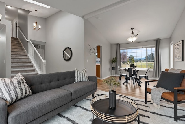 living area featuring stairway, wood finished floors, baseboards, lofted ceiling, and a chandelier