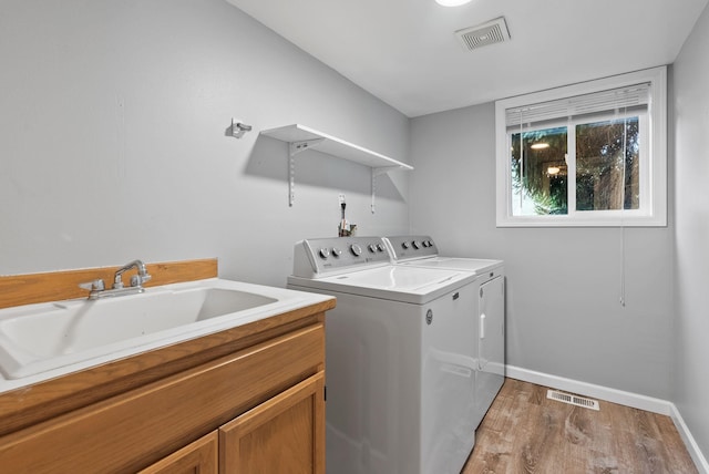 laundry area featuring washing machine and clothes dryer, visible vents, cabinet space, and a sink