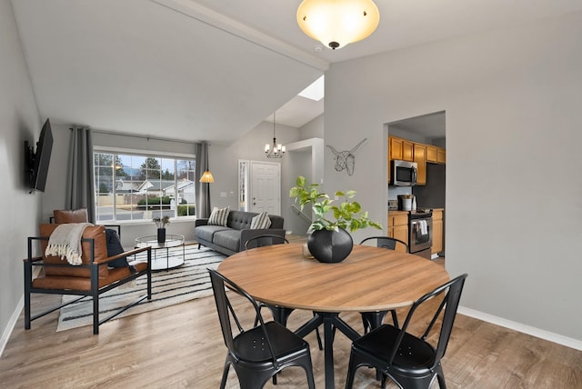 dining room featuring a notable chandelier, light wood-style flooring, lofted ceiling with beams, and baseboards