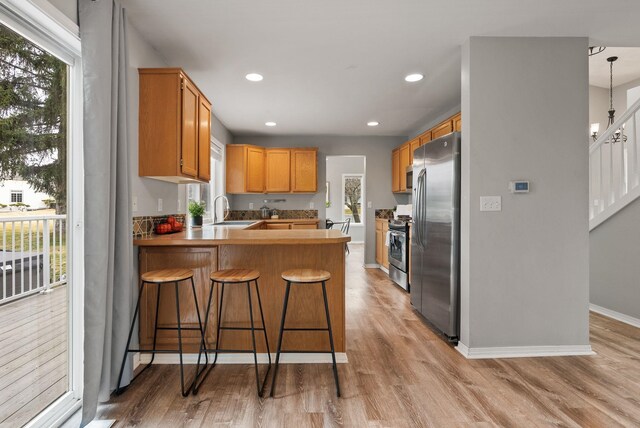 kitchen with light wood-style flooring, a sink, recessed lighting, stainless steel appliances, and a peninsula