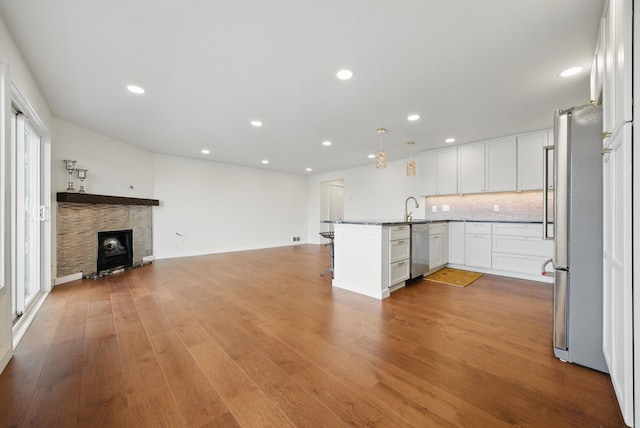 kitchen with light wood-type flooring, open floor plan, freestanding refrigerator, and a sink