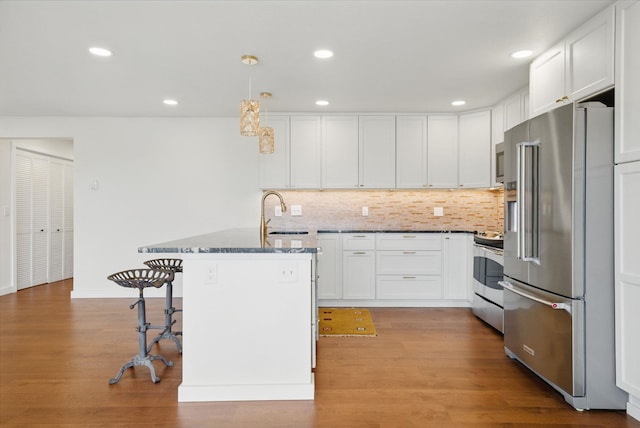 kitchen with dark stone countertops, light wood-style flooring, a sink, stainless steel appliances, and white cabinetry