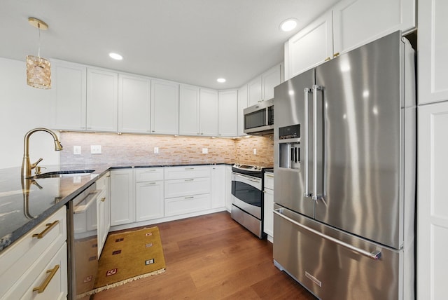 kitchen featuring dark wood finished floors, tasteful backsplash, appliances with stainless steel finishes, and a sink